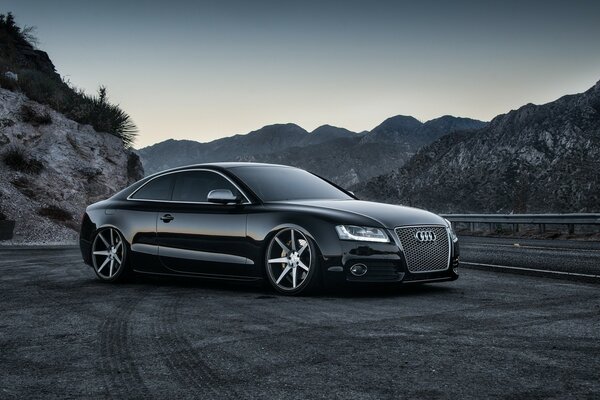 Audi noir sur la route dans la nuit dans les montagnes