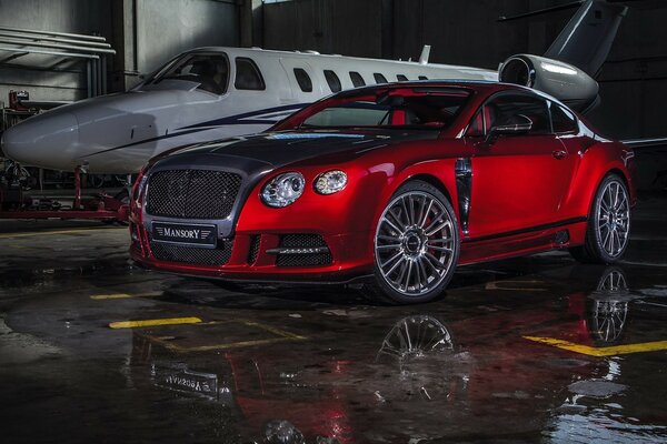 Bentley mansory rouge près de l avion