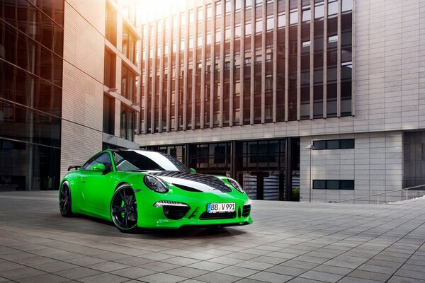 Zielone Porsche z czarnymi akcentami na tle nowoczesnego budynku w promieniach słońca