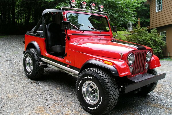 A red car on the asphalt near the house