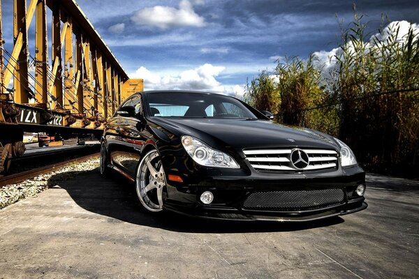 Mercedes Benz nero si trova di fronte alle carrozze ferroviarie