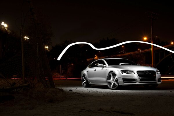 A gray Audi is parked on a dark street