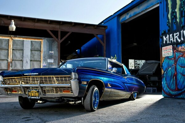 Blue lowrider car near the garage