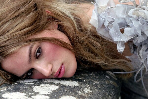 Keira Knightley is lying face down on a rock