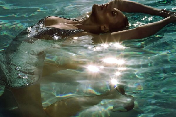 Fille en maillot de bain arqué dans la piscine