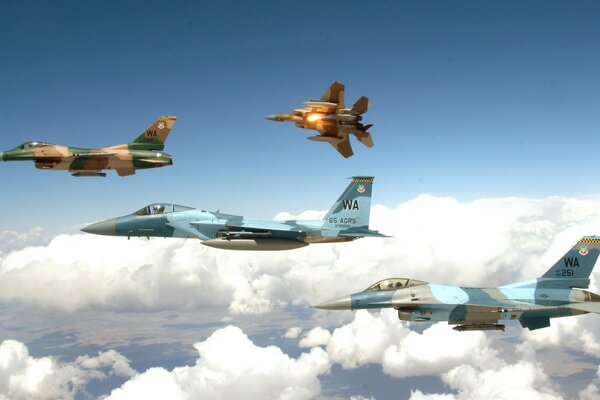 Several fighter jets are flying above the clouds