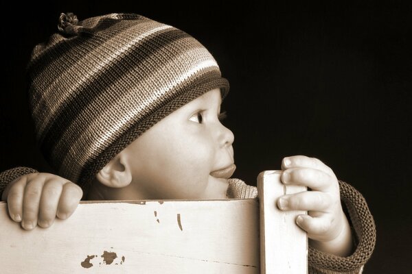 Bambino in un cappello a righe di profilo su sfondo nero