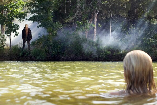 Mädchen im Wasser schaut den Kerl am Ufer an