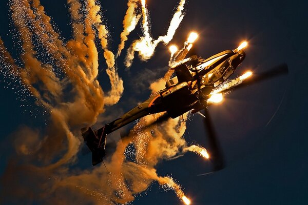 El helicóptero apache gira por la noche en el cielo con luz brillante