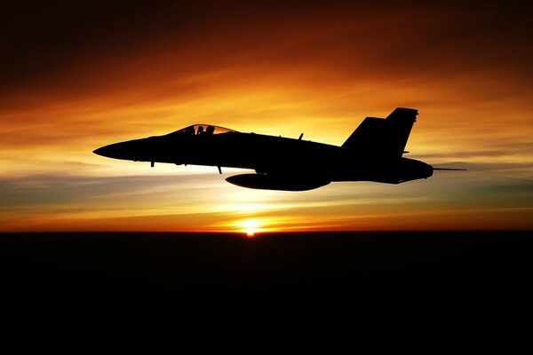 Avion militaire vole sur fond de coucher de soleil