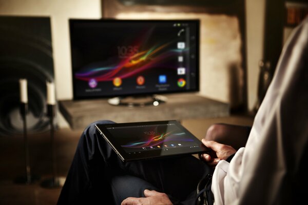 Uomo con tablet in ginocchio davanti alla TV