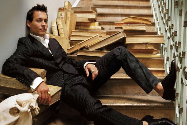 Johnny Depp on the stairs among the scattered books