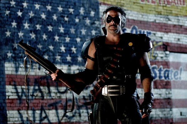 A man with a gun and ammunition on the background of the US flag