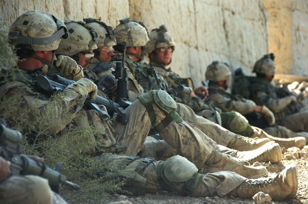 Отдыхающие, сидящие около стены солдаты в форме