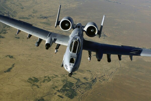 A large military plane flies over the ground