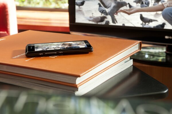 The switched-on phone is lying on a stack of books