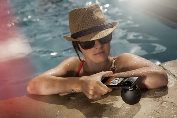 Mädchen im Pool hält ein Telefon in der Hand