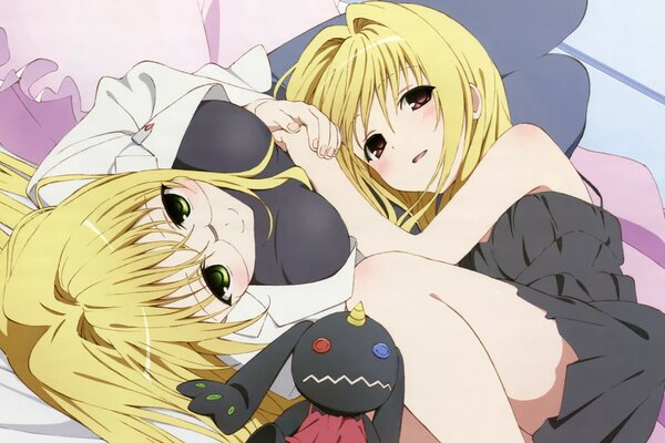 Two girls with blonde hair are lying in an embrace