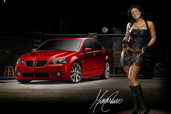 A girl in a black dress on the background of a red car