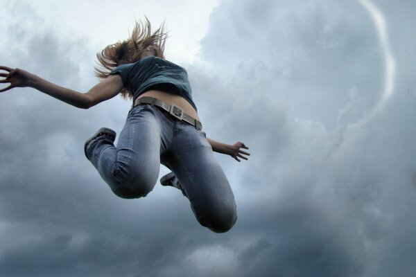 Saut vers le haut, fille sur fond de ciel