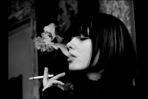 Beautiful girl smokes, black and white photo of a brunette girl smoking