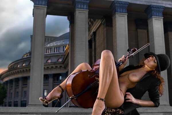 Chica desnuda con un instrumento musical entre las piernas