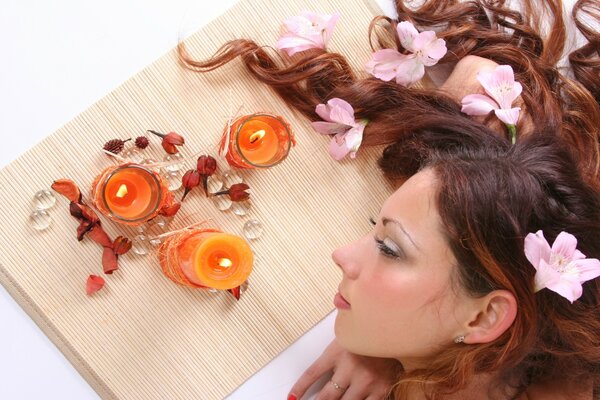 Ragazza sdraiata con candele e fiori tra i capelli