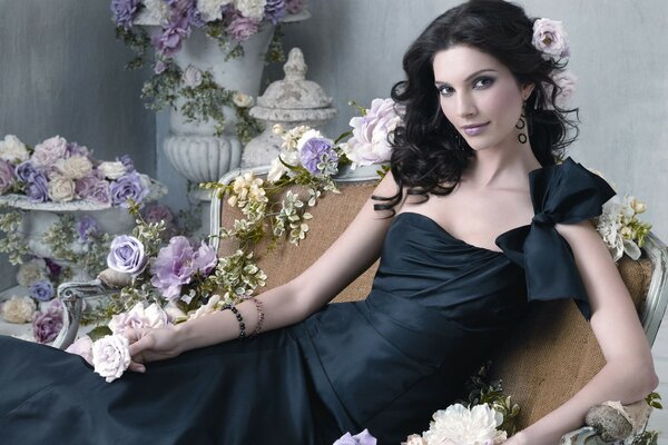 Chica con vestido negro sobre fondo de flores