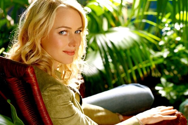 La actriz Naomi Watts en una silla entre las plantas