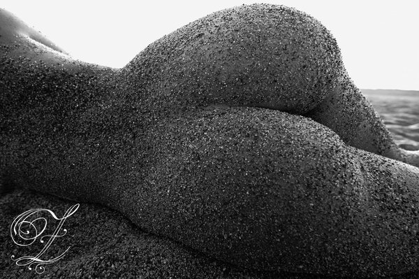 Black and white photo of a naked ass in the sand close-up