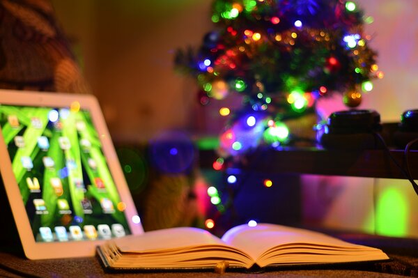 Arbre de Noël dans la chambre. Tablette et livre sur la table