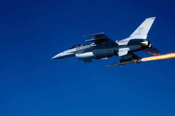 A military plane in a clear sky releases a rocket