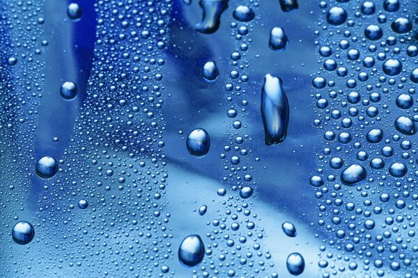 Gotas de agua azules en el vidrio