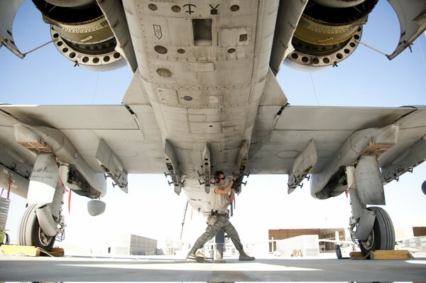 The plane is gray next to a man preparing to fly