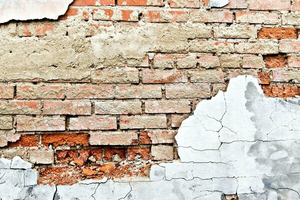 Brick wall with crumbling plaster and cracks