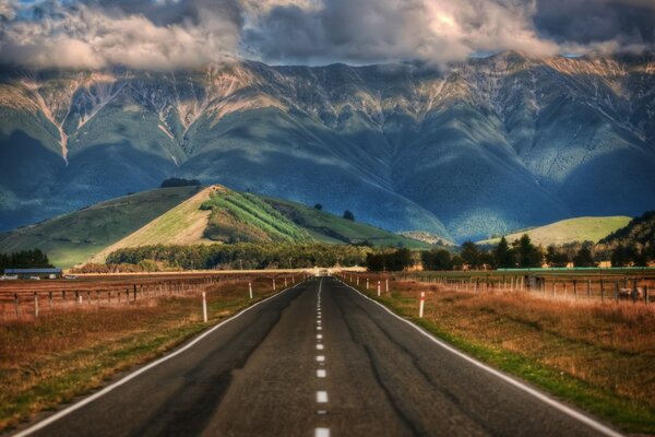 Strada circondata da campi con vista sulle colline e sulle montagne della Nuova Zelanda