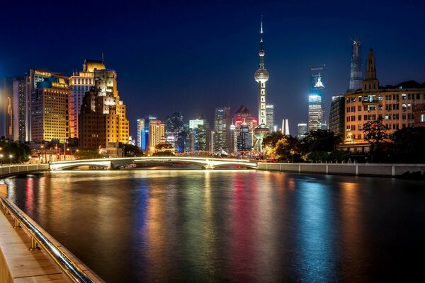 Los rascacielos de Shanghai brillan con luces en la noche y se reflejan en el río