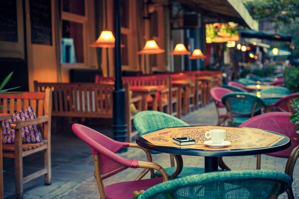 The colorful tables of the summer cafe are illuminated by cozy lamps