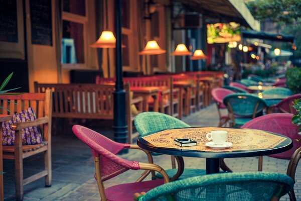 I tavoli multicolori del caffè estivo sono illuminati da lampade accoglienti