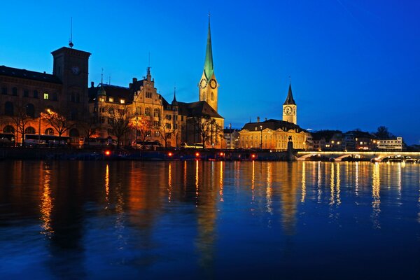 Zurich at night is reflected in a dark river