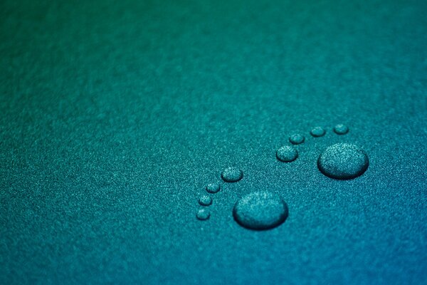 Minimalismo sobre un fondo turquesa, con gotas de agua y huellas de pies sobre una superficie azul
