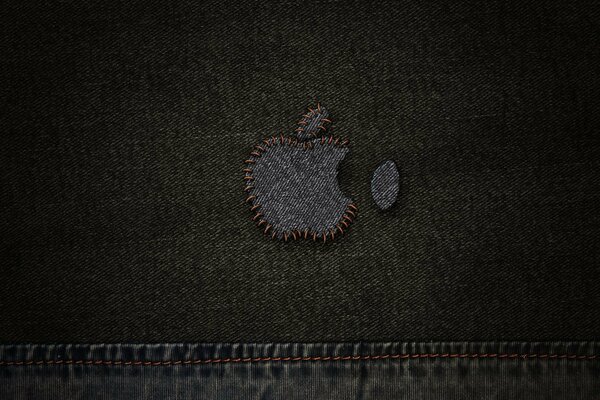 An apple is sewn with threads to jeans