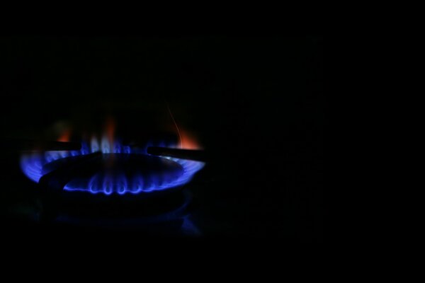 Quemador de gas sobre fondo negro. Llama azul y roja
