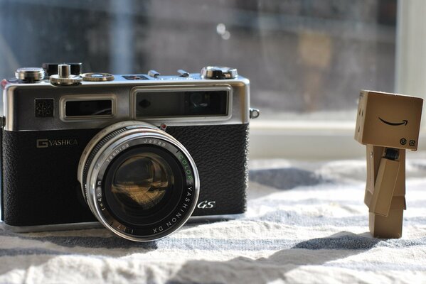 A camera and a wooden man on a crumpled cloth