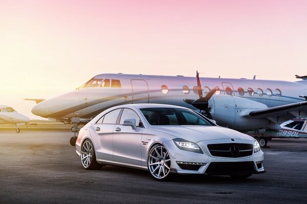 Un avión privado está al lado de un automóvil extranjero