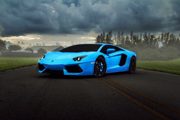 Blauer Lamborghini Aventador auf Hintergrund der Straße mit Wolken