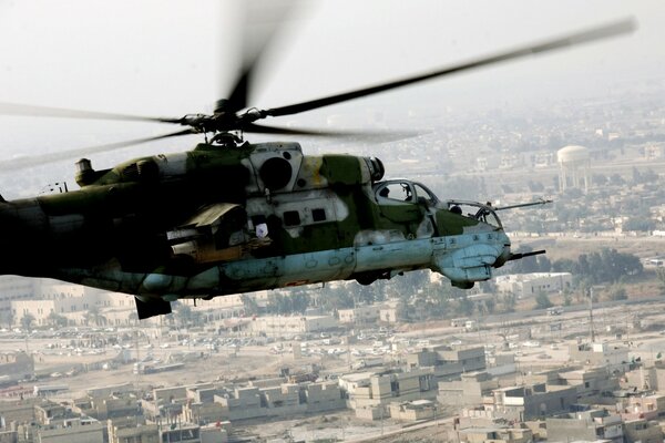 Camouflage helicopter of the USSR flies over the city