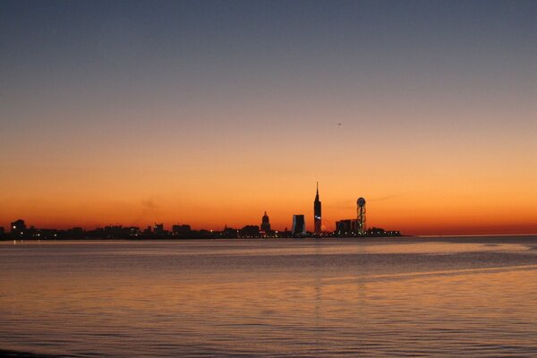 Schöne Stadt in der Nähe des Meeres vor dem Hintergrund des Sonnenuntergangs