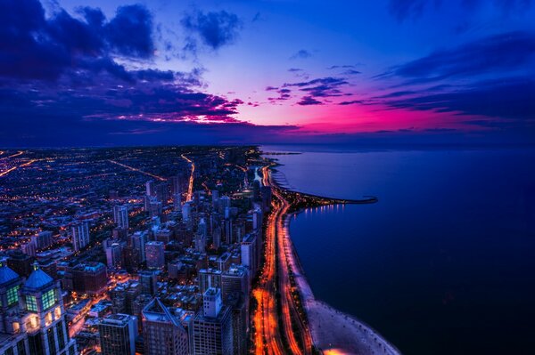 Una ciudad animada por la noche y un océano tranquilo