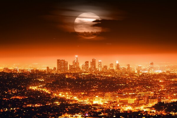 The moon over the lights of the metropolis at night